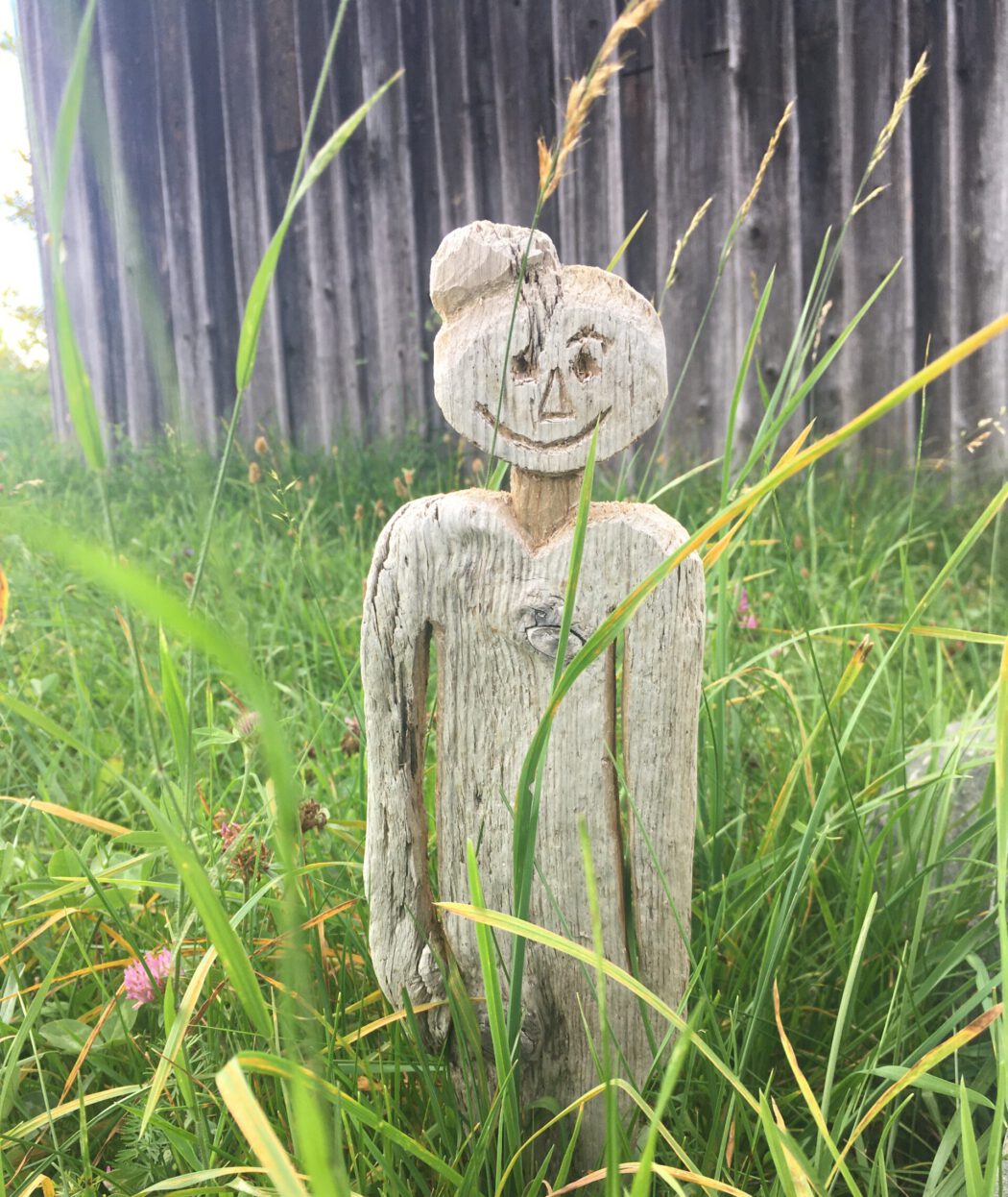 Holzfigur im Gras als Symbol für Achtsamkeit und innerer Einkehr