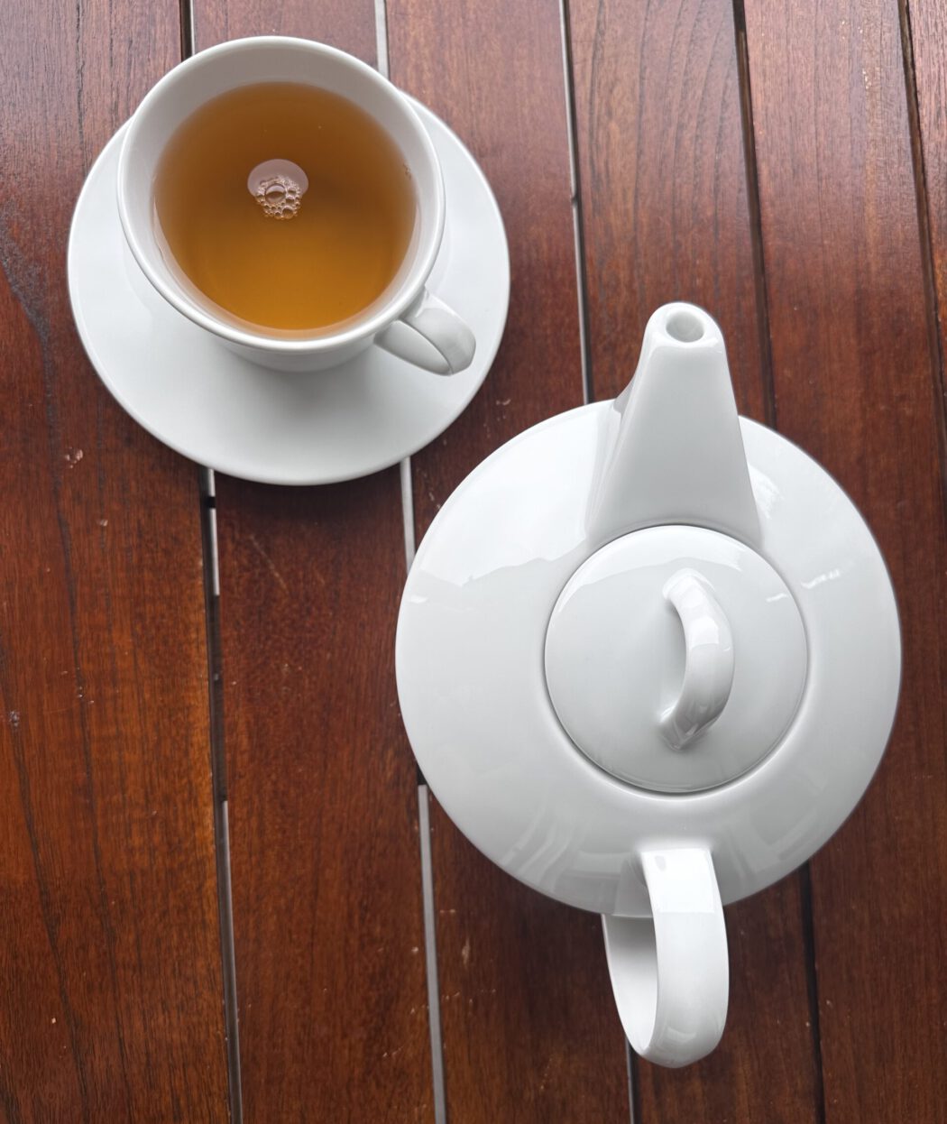 Tasse Jasmintee und weiße Teekanne auf einem Holztisch im Tessin