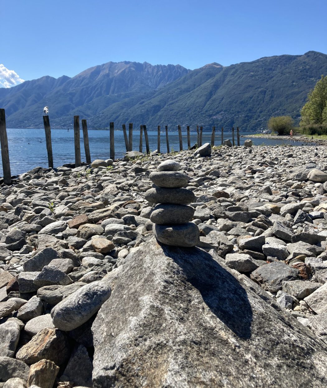 Bild am See mit aufgestapelten Steinen als Sinnbild für Meditation